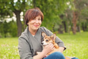 A portrait of a middle aged woman holding her corgi.