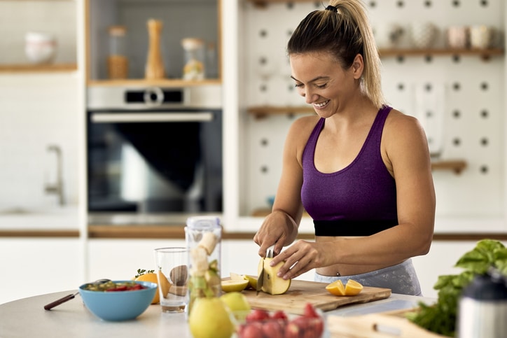 A woman cutting fruit in her kitchen.