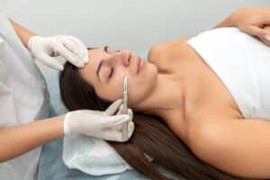 Woman lying on table undergoes cosmetic dermaplaning treatment